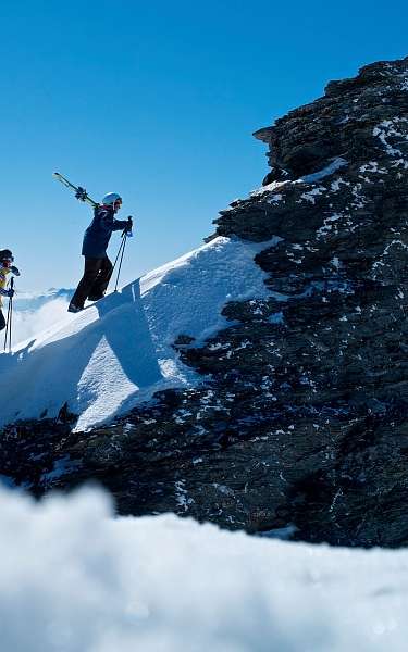 Zwei Skifahrer tragen ihre Skier im Schneeurlaub den schneebedeckten Berg hinauf 